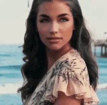 a woman in a floral dress is standing on a beach near the ocean .