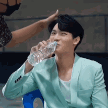 a man in a green suit drinking from a bottle