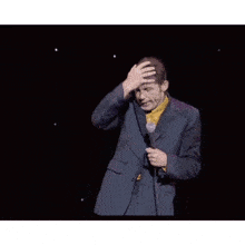 a man in a suit is dancing on a stage with a microphone .