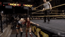 two women are wrestling in a wrestling ring with the word nxt on the wall