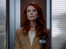 a woman with red hair has a visitor tag on her jacket