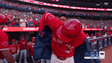 a baseball player wearing a red blue jays jersey is being lifted by another player
