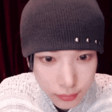 a close up of a person wearing a beanie and a sweater