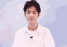 a young man wearing a white shirt has a microphone attached to his shirt