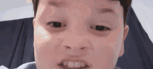 a close up of a young boy making a funny face with his mouth open .