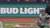 a baseball player catches a ball in front of a bud light ad