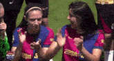two female soccer players are applauding each other on a field sponsored by arsenal