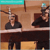 two men singing into microphones with the hashtag #archivesgroupem6 on the bottom
