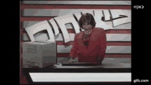 a woman in a red jacket is typing on a keyboard in front of a sign that says 11
