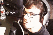 a man wearing glasses and headphones is sitting in front of a microphone ..