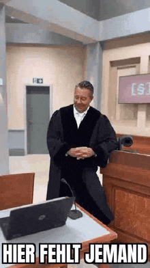a judge is standing in front of a laptop in a courtroom .