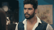 a man with a beard is wearing a white shirt and a vest