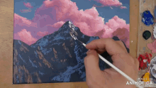 a person is painting a mountain with pink clouds and the words made in animatica