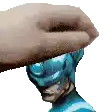 a hand is holding a statue of a superhero 's head in front of a white background .