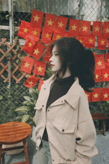 a girl stands in front of a wall of flags with yellow stars on them