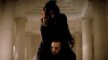 a woman is sitting on top of a man 's shoulders in a hallway .