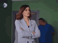 a woman with her arms crossed stands in front of a green wall