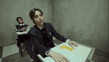 a man in a suit is sitting at a desk with a letter p on it