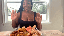 a woman sitting at a table with a plate of food and a box that says crab claw