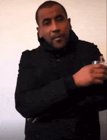 a man in a black jacket is holding a can of soda in his hand
