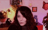 a woman wearing headphones looks at the camera in a room with stuffed animals on the wall