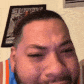 a man with a beard is crying in front of a framed picture of a man .