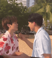 a couple of men standing next to each other on a beach with palm trees in the background