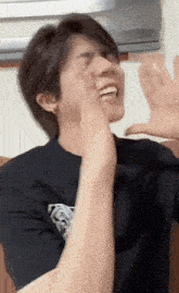 a man is making a funny face with his hands while wearing a black shirt .