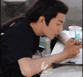 a man with a ponytail is sitting at a table looking at a cell phone