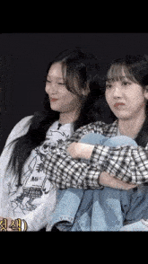 two girls are sitting next to each other with their arms crossed and one of them is wearing a shirt with a cartoon on it
