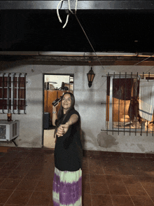 a woman in a tie dye skirt is holding a microphone in her hand
