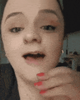 a close up of a woman 's face with red nail polish
