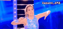a woman in a blue sequined dress giving a thumbs down sign