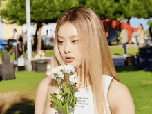 a woman with blonde hair is holding a bouquet of flowers