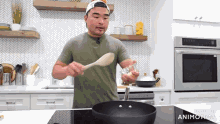 a man is cooking in a kitchen with a wooden spoon in his hand .