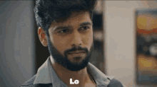 a man with a beard is looking at the camera and the word lo is on the bottom of his face