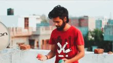 a man in a red shirt holds an apple and a ball
