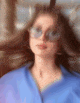a blurry picture of a woman wearing glasses and a blue shirt