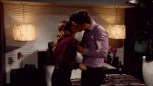 a man and woman are kissing in a bedroom with lamps hanging from the ceiling