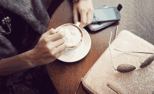 a woman is sitting at a table drinking a cup of cappuccino