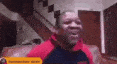 a man is sitting on a couch with his mouth open and a sign that says dominique davis $ 10.00