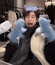 a man wearing blue gloves is sitting in front of a microphone with chinese writing on his head