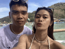a man and a woman are posing for a picture with a boat in the background that says ' sss ' on it