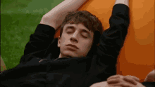 a young man is laying on a couch with his eyes closed and his arms outstretched .