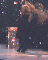 a woman in high heels is dancing on a stage with a drum set in the background
