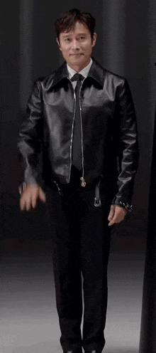 a man in a leather jacket and tie is waving his hand .