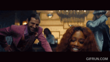 a man in a pink suit and a woman with red hair are dancing in a club ..