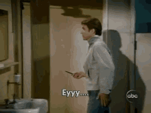 a man standing in a bathroom with eyyy written on the bottom of his face