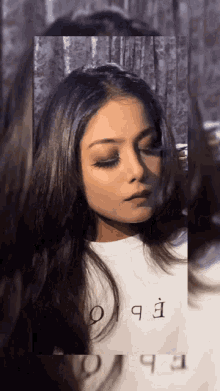 a woman with long hair is wearing a white shirt that says ' ebc ' on it