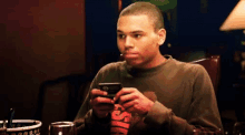 a man sitting at a table looking at a cell phone with the letter s on it